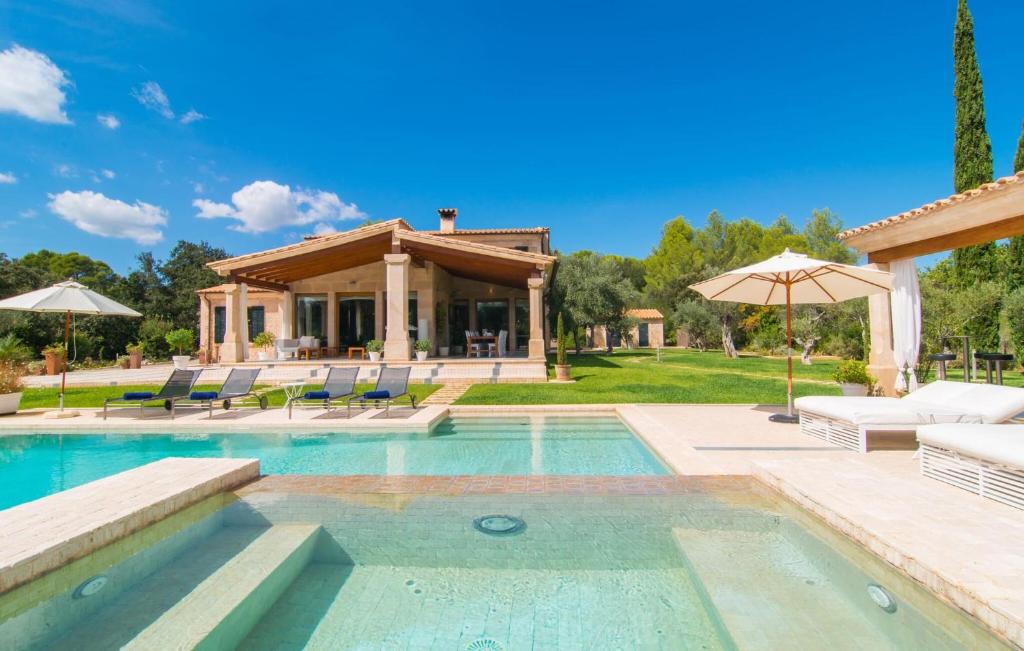 a pool with chairs and umbrellas next to a house at Golf Marina in Pollença