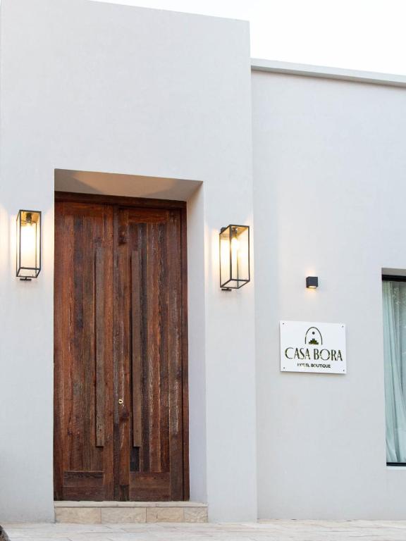 a wooden door in a white building with a sign at Casa Bora Hotel Boutique in San Antonio de Areco