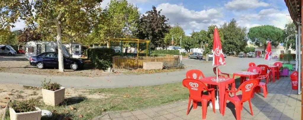 a group of red tables and chairs in a park at ZEcamping 3 étoiles aire de jeux multi-activités in Toulouse