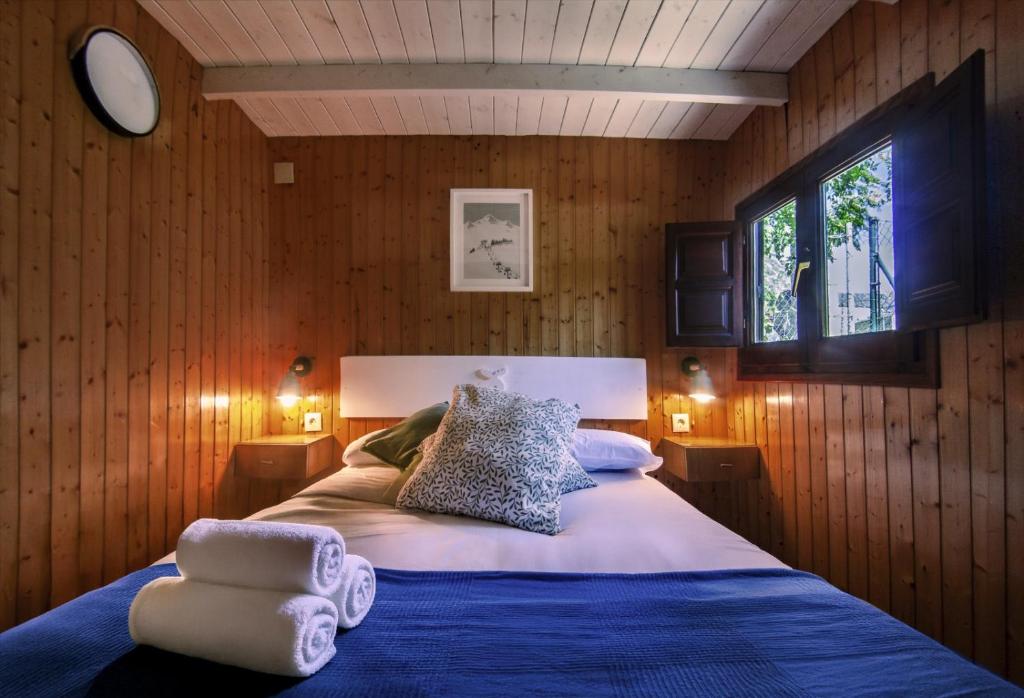 ein Schlafzimmer mit einem Bett mit blauer Bettwäsche und einem Fenster in der Unterkunft Camping Boneta in Barruera