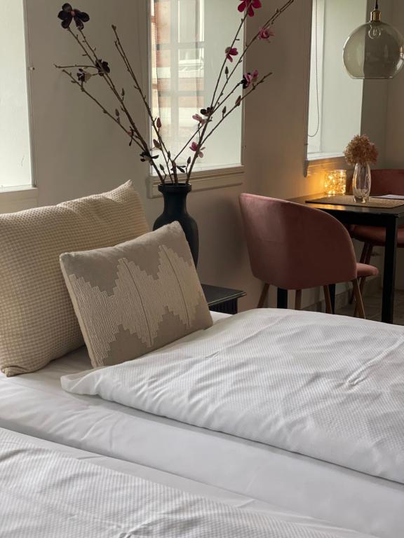 a bed with a pillow and a vase with flowers at Carlsminde ferielejlighed in Stenstrup