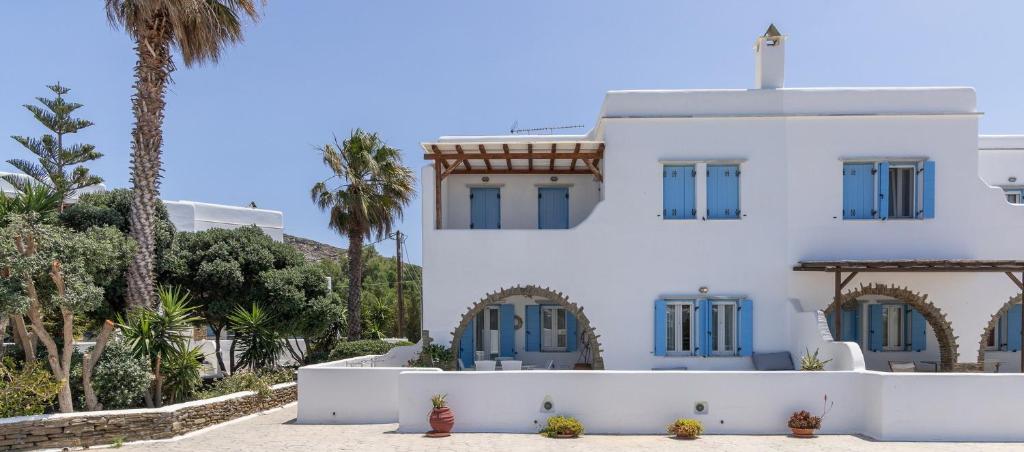 a white house with blue windows and palm trees at Home sea home in Agios Ioannis