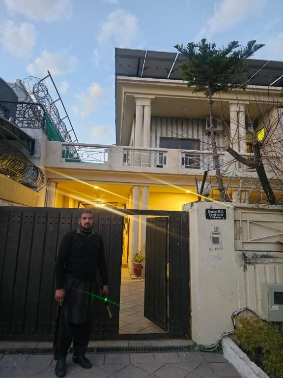 a man standing in front of a house with a green lightsaber at Ambassador Suites in Dargai