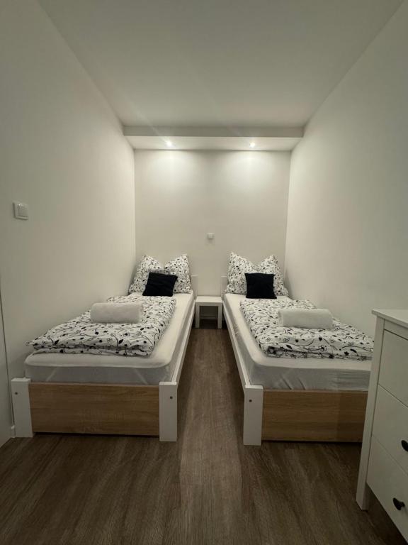 two beds in a room with white walls and wooden floors at RK Apartment in Brno