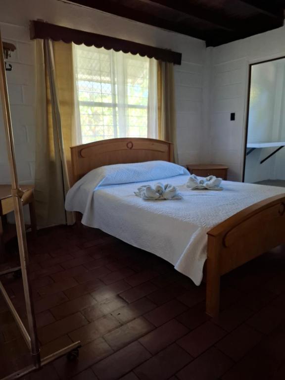 a bedroom with a bed with white sheets and a window at Coco Beach House in Coco