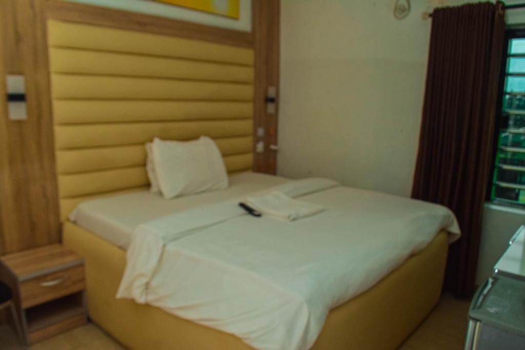 a bedroom with a bed with a white sheets and a remote control on it at Greystone Hotel in Asaba