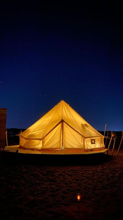a large yellow tent on the beach at night at Sahara Dream Camp in Al Raka