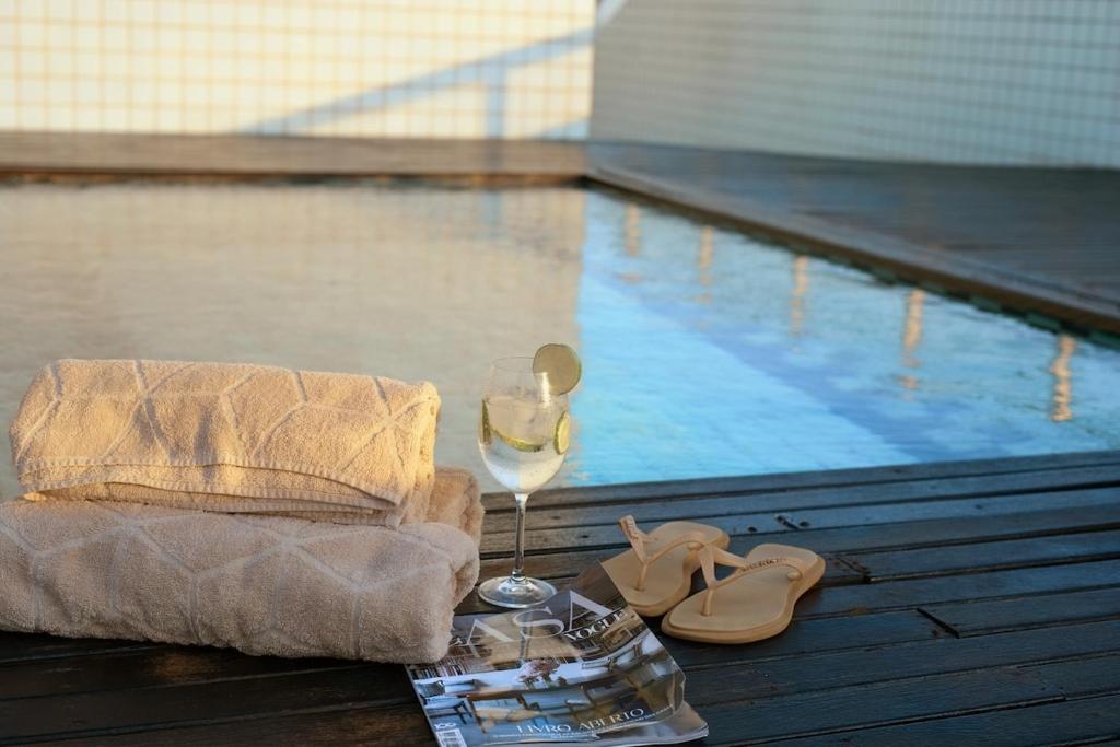 a glass of wine next to a swimming pool at Cobertura Duplex a Beira-Mar de Capão da Canoa in Capão da Canoa