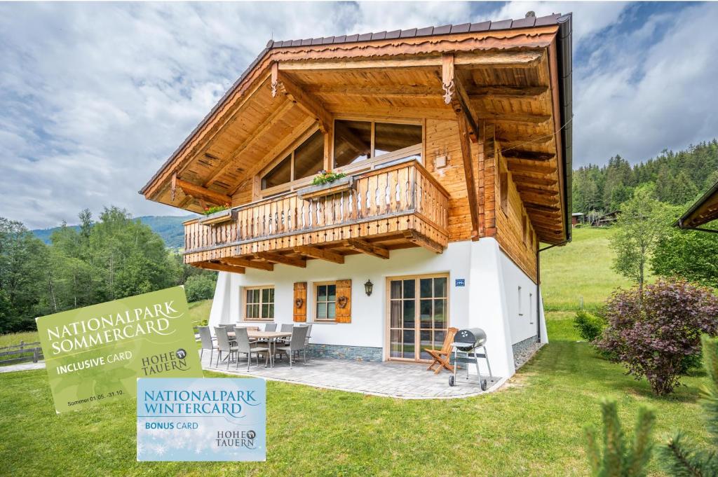 a tiny house with a large deck on a lawn at Chaletdorf am Sonnenhang in Neukirchen am Großvenediger