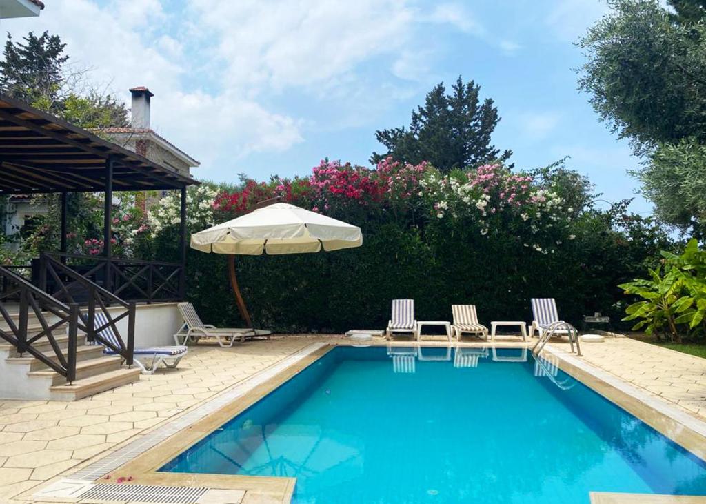 a swimming pool with two chairs and an umbrella at Villa Cyprium in Kyrenia