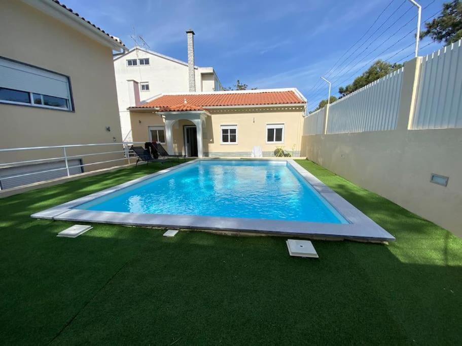 a swimming pool in the yard of a house at Cozy House in Charneca