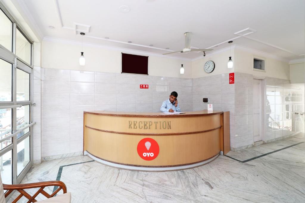 a man sitting at a reception desk in a room at Hotel O Mehtab Regency in Rewāri
