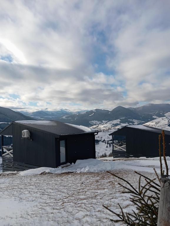 two buildings in the snow with mountains in the background at AFTERGLOW verkhovyna in Iltsi