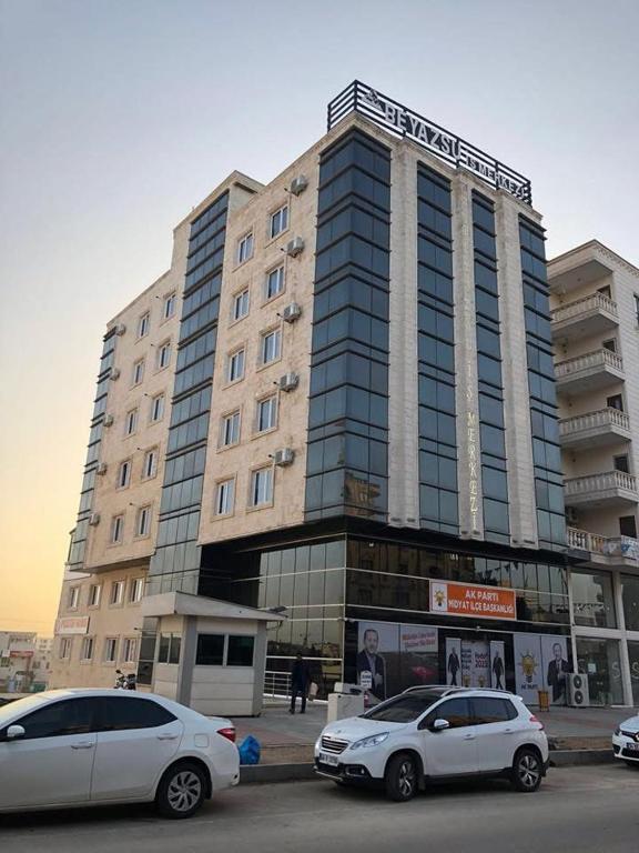 two cars parked in front of a large building at Beyaz Suites in Midyat