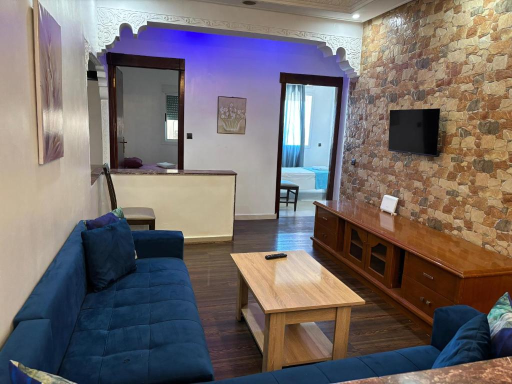 a living room with a blue couch and a tv at Casandalus in Larache