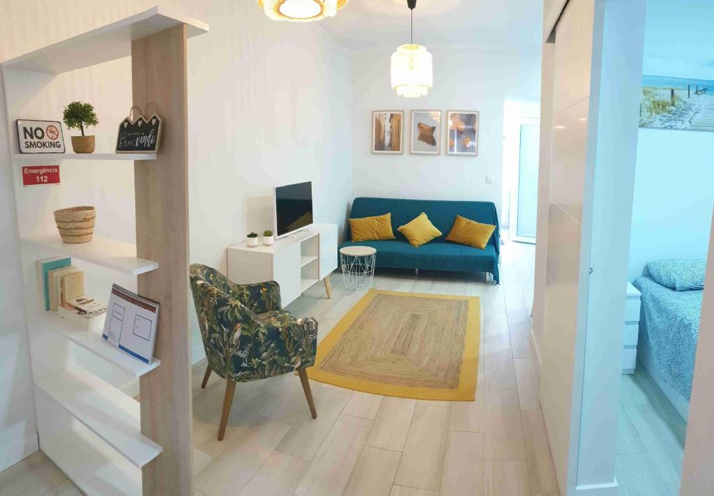a living room with a blue couch and a chair at Casa Belice in Vila Real de Santo António