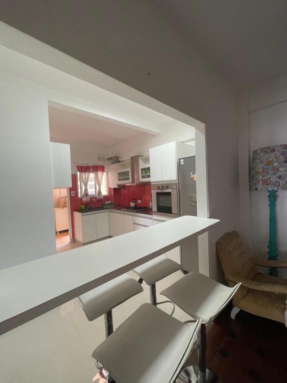 a kitchen with a white counter and some chairs at Miramar2026 in Miramar