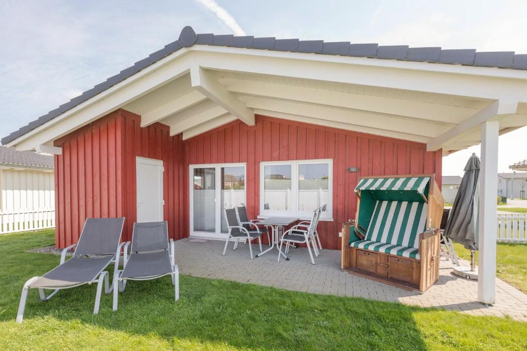 a red shed with chairs and a table and a roof at Ferienhaus Strandflieder in Dagebüll