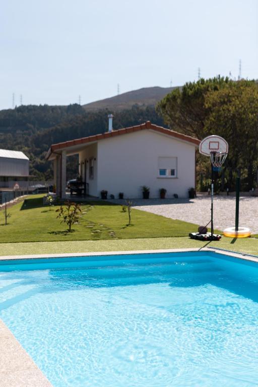 a swimming pool with a basketball hoop in front of a house at Encosta da Cabreira in Vieira do Minho
