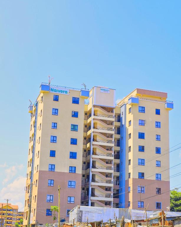 a tall apartment building with blue windows at Naivera Membly Star Heights in Ruiru