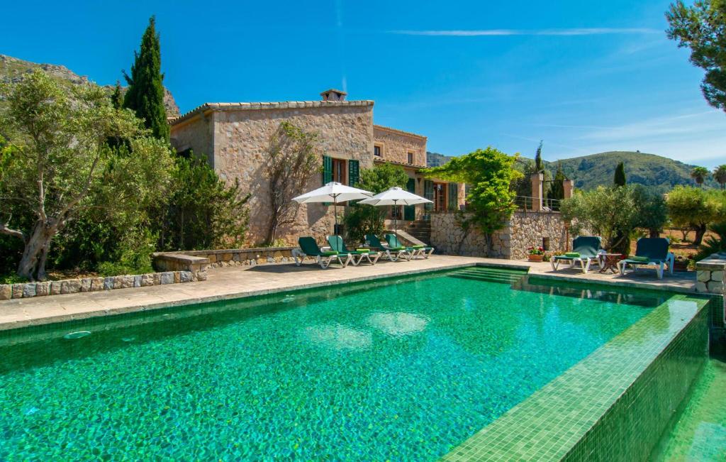 a pool with chairs and umbrellas next to a house at Villa Maria De Betlem in Colonia de Sant Pere