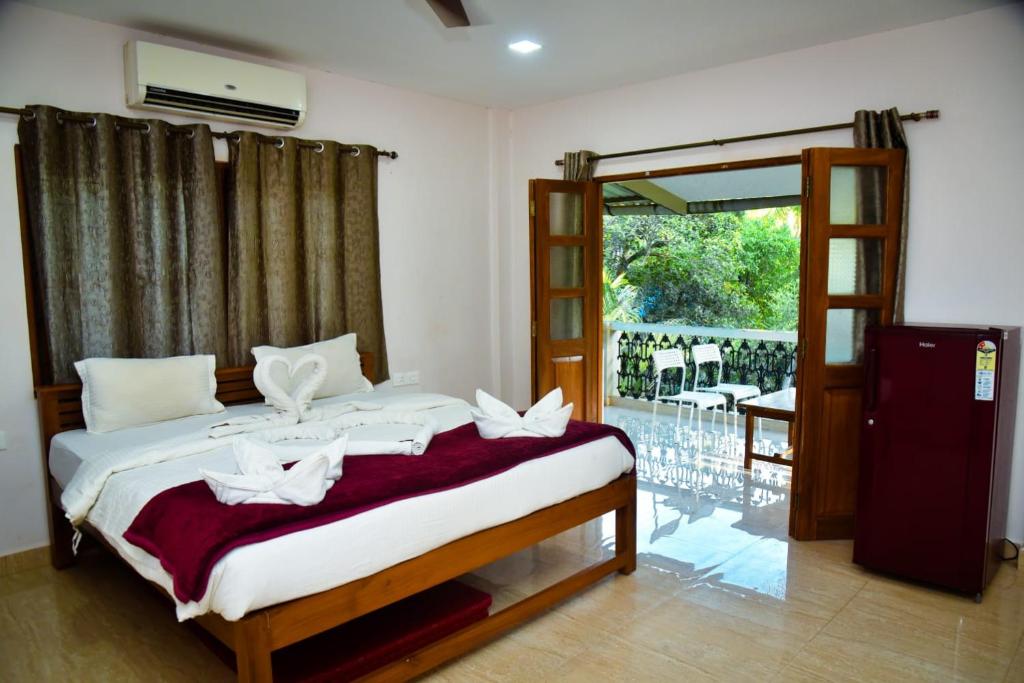 a bedroom with a bed and a balcony with chairs at Wayne Nest Calangute in Calangute