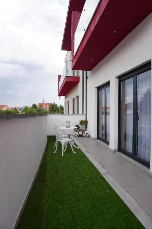 a balcony with two white chairs and grass at Casa do Pessegueiro in Mirandela
