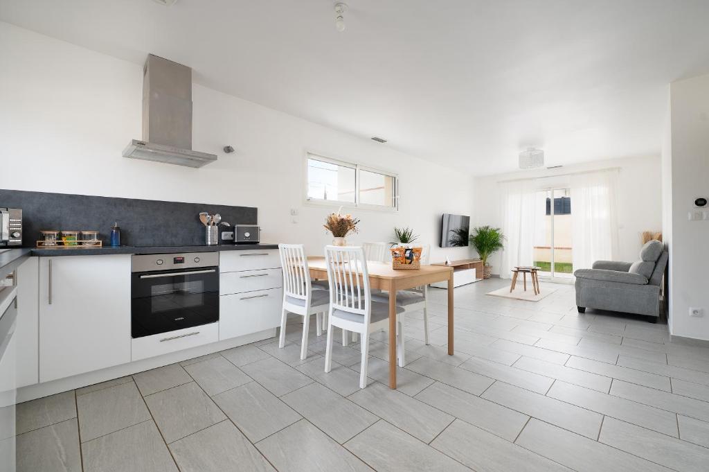 a kitchen with white cabinets and a table and chairs at Évasion à Bruguières in Bruguières