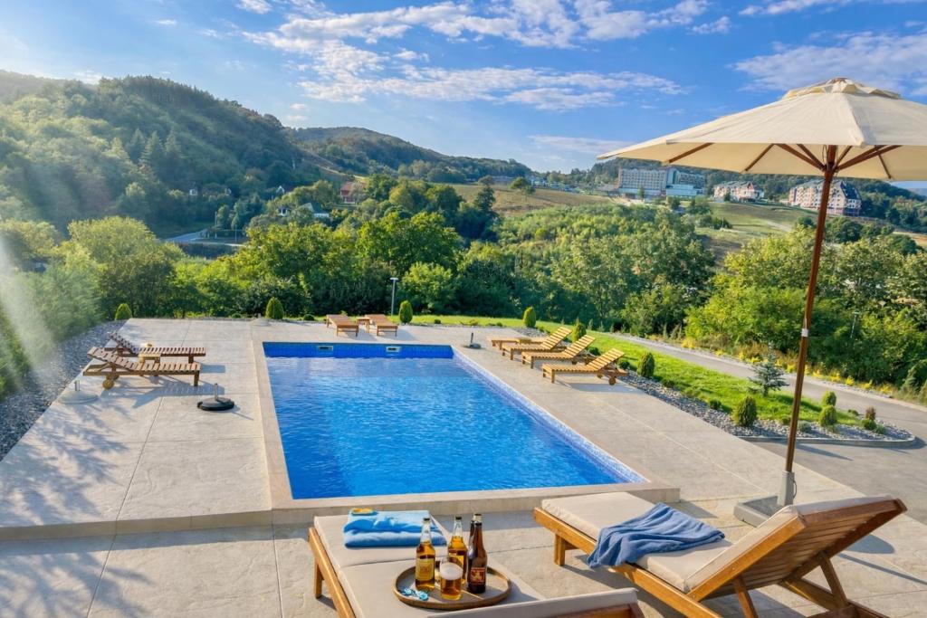 a swimming pool with chairs and an umbrella at Green panorama Vrdnik in Vrdnik