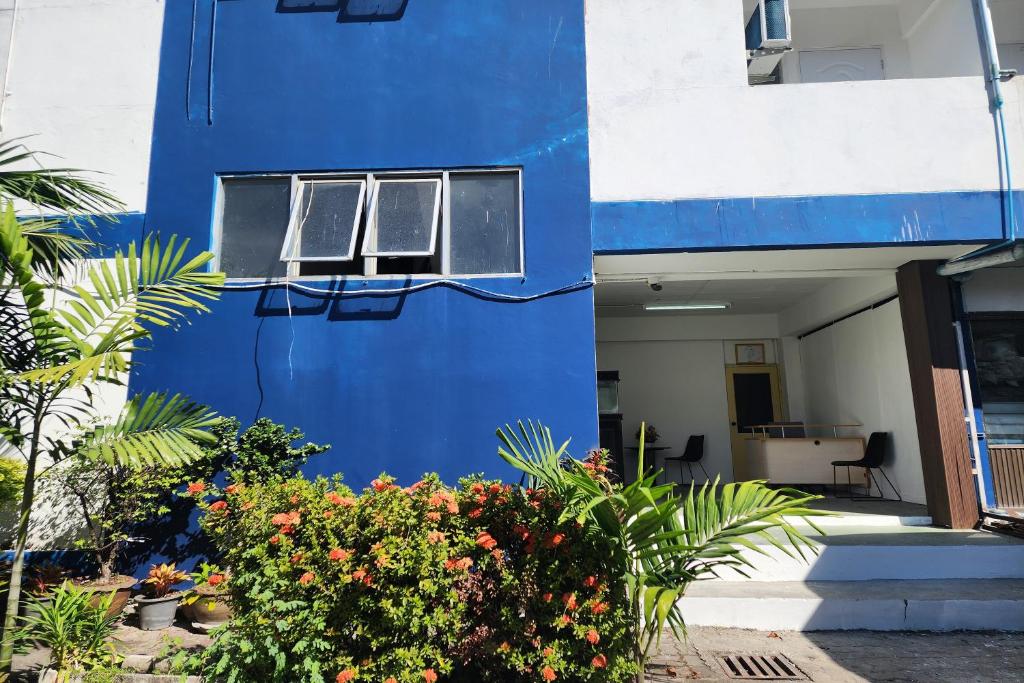 a blue building with a window and some plants at Toucan Garden in Samutprakarn
