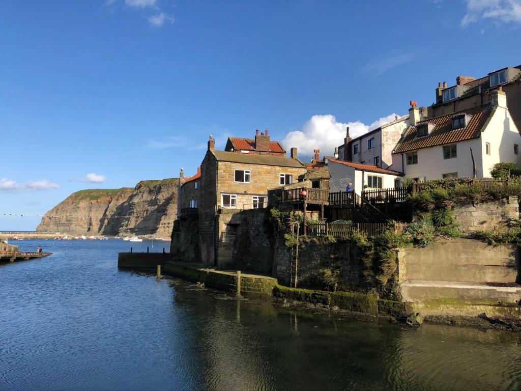 a group of houses on a cliff next to the water at Cliff Crest Cottage in Staithes