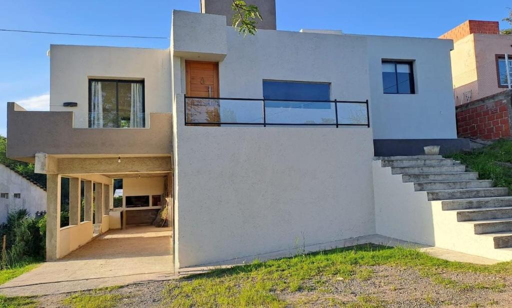 a white house with a balcony and stairs at Casa- alojamiento Gerez in San Antonio de Arredondo