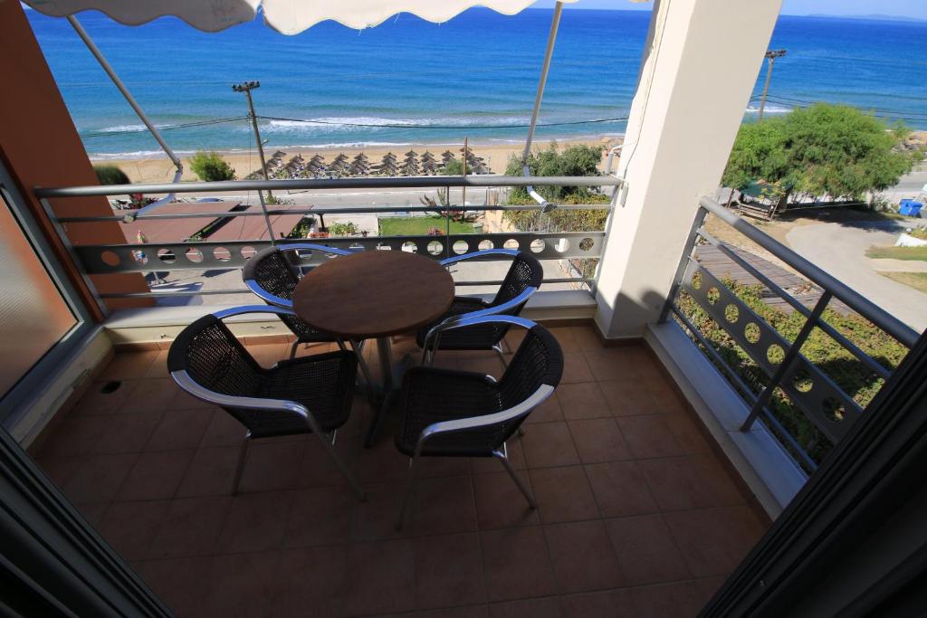 a balcony with a table and chairs and the beach at Platis-Gialos apartments in Loutsa