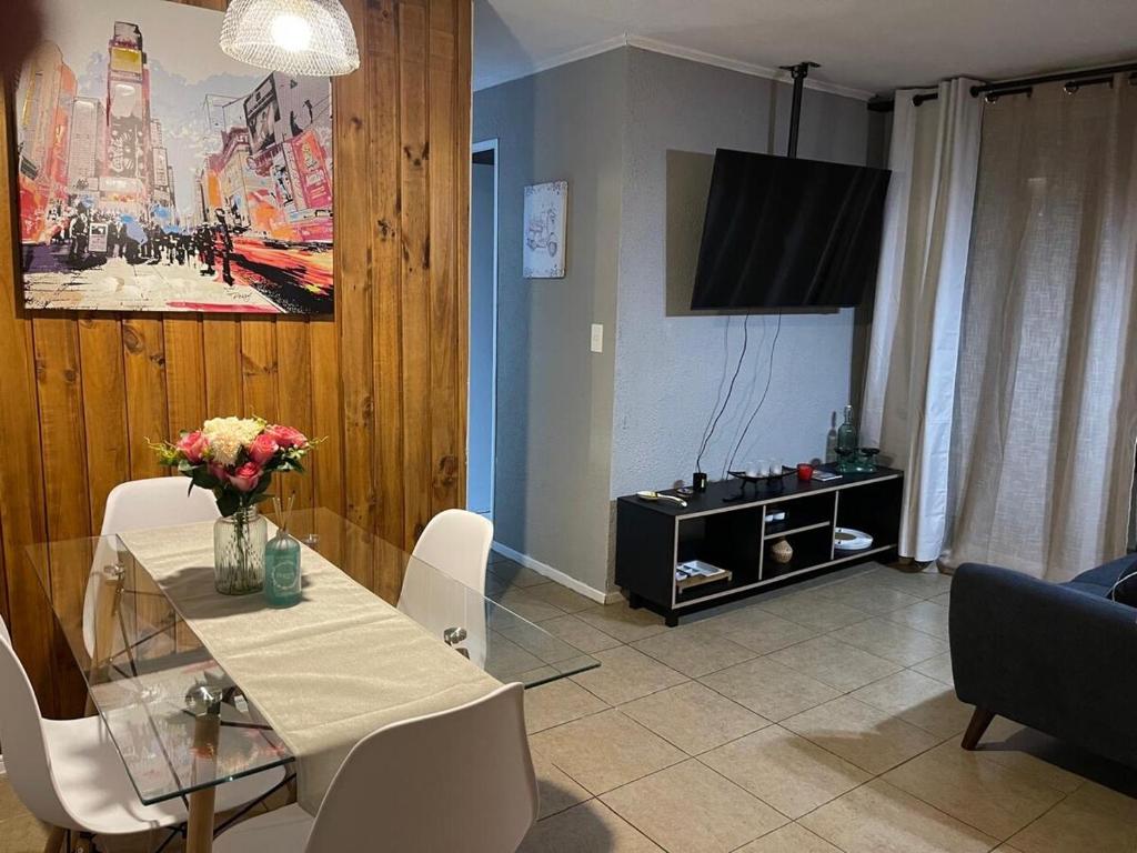 a living room with a table and a television at Departamento outlet Puerto Montt con estacionamiento in Puerto Montt