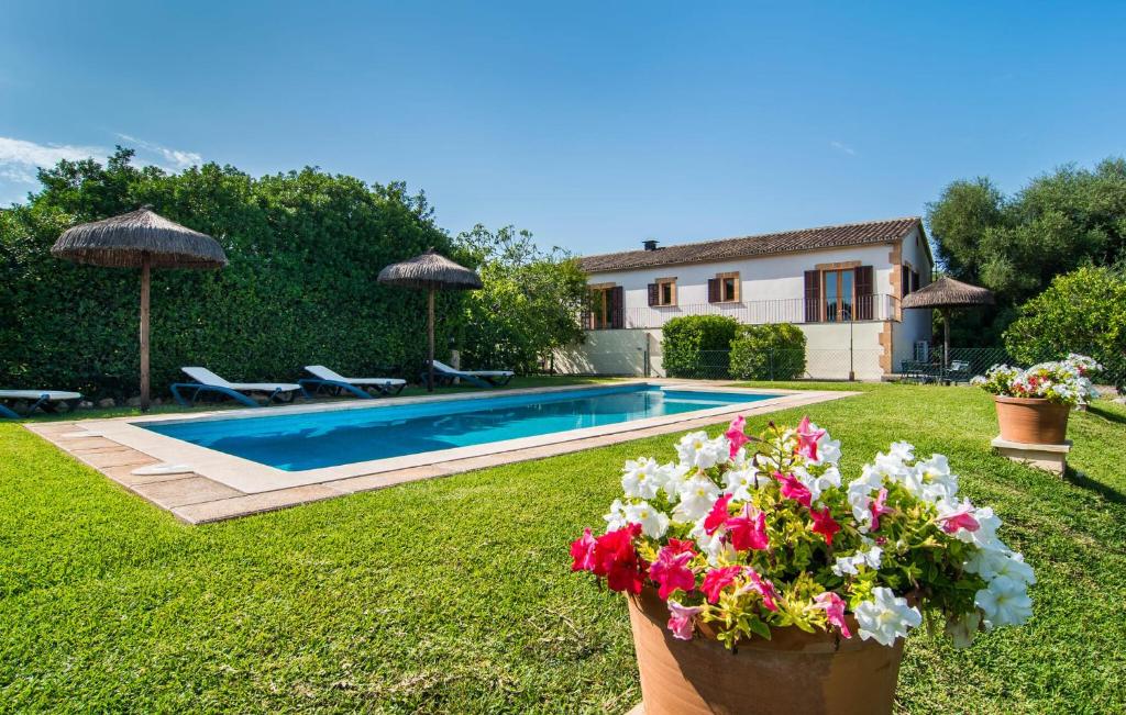 a villa with a swimming pool and flowers in a yard at Can Polito in Can Picafort