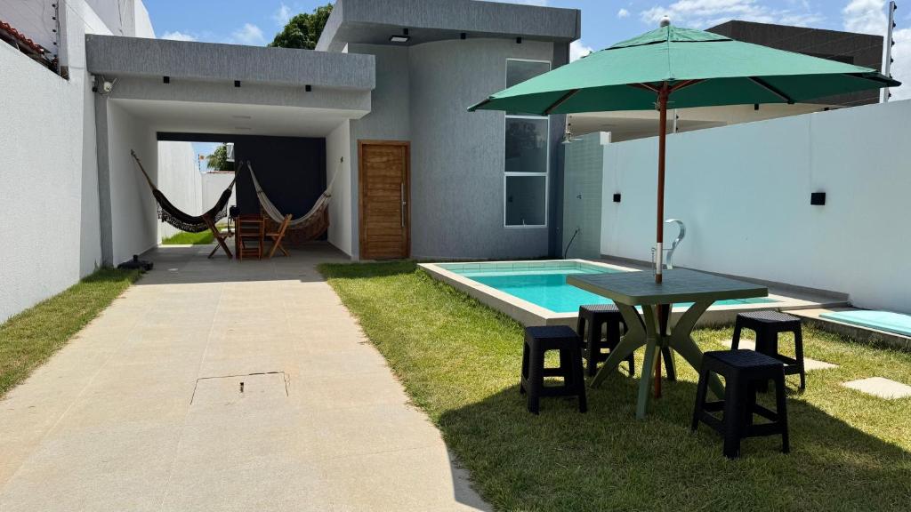 a patio with a table and an umbrella next to a pool at Bela casa jacumã in Conde