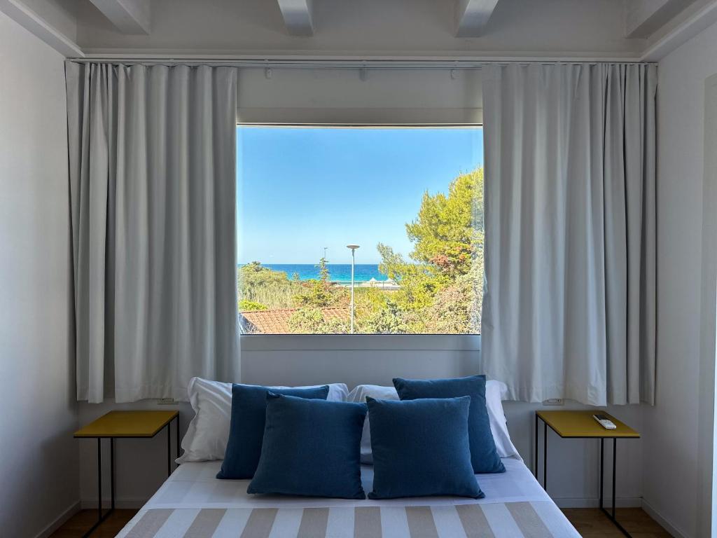 a bed with blue pillows in front of a window at ItineraBaiaVerde Rooms & Breakfast in Gallipoli
