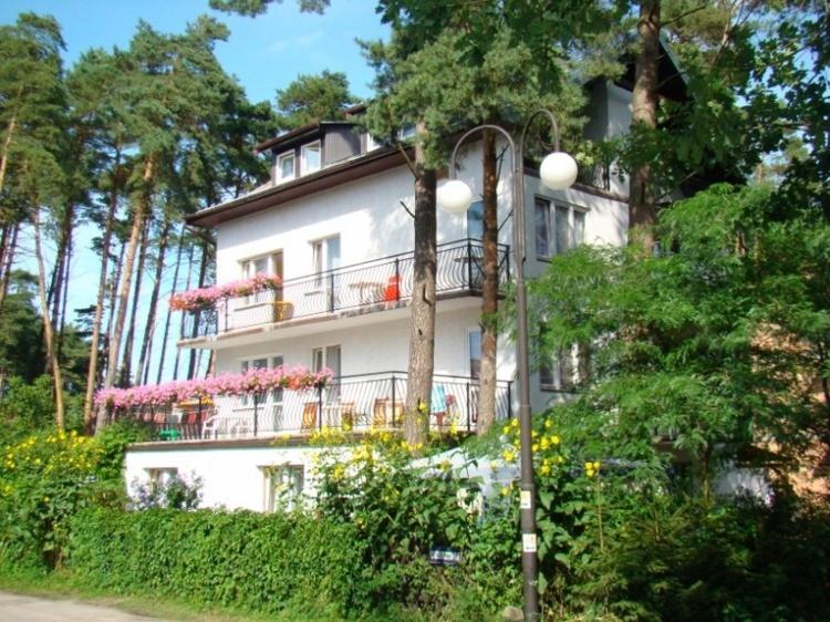 a large white building with a balcony and a street light at Pod Sosnami 46 in Pobierowo
