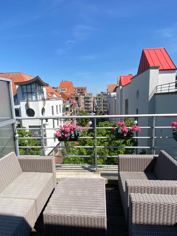 a balcony with wicker chairs and flowers on a building at Charming Duplex in Knokke-Heist