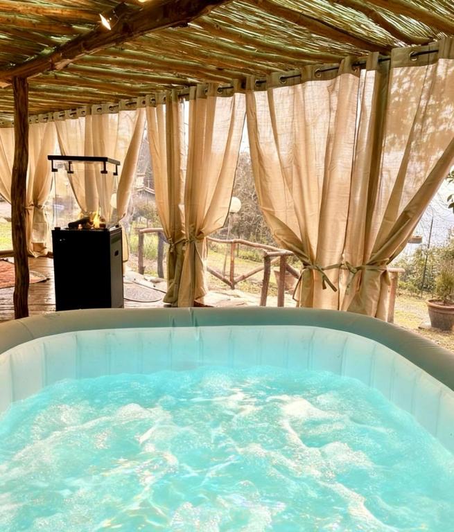 a jacuzzi tub in an outdoor room with curtains at Agriturismo Tassinaia in Pontassieve
