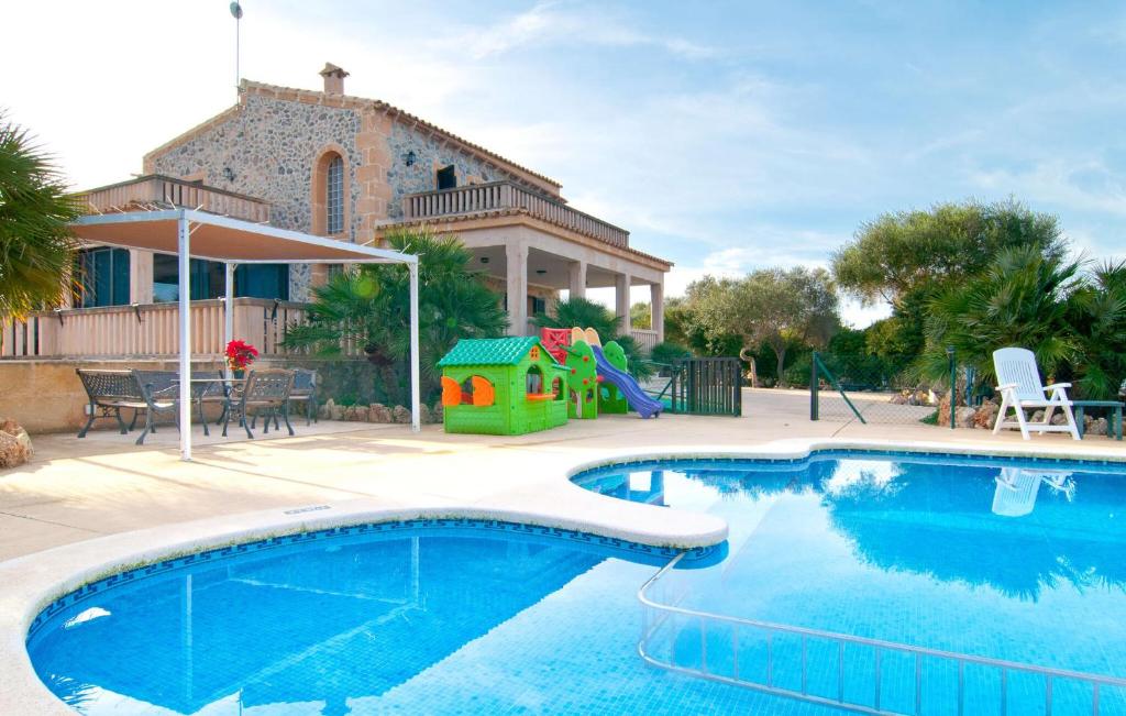 a swimming pool with a playground and a house at Finca Sa Pedrera in Can Picafort