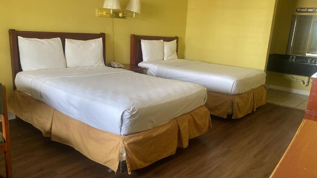 two beds in a hotel room with white sheets at Evergreen Plaza Inn in Metairie