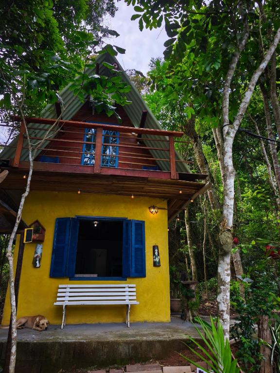 a yellow house with a bench in front of it at Chalé no Plantar em Casa in São Roque