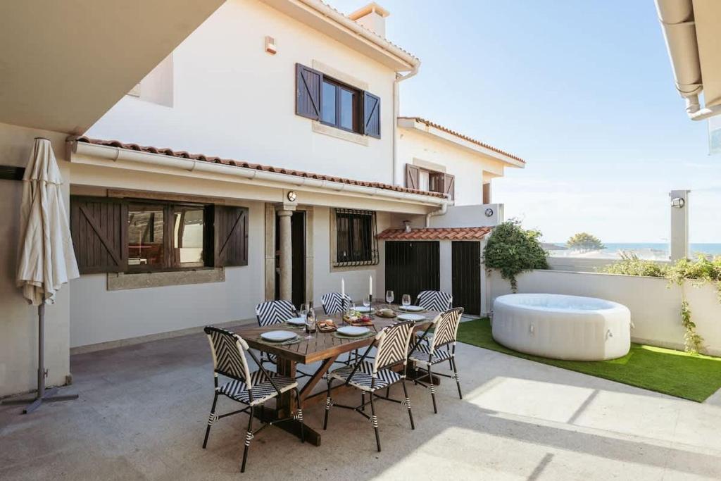 a patio with a table and chairs and a tub at Beach Villa with Jacuzzi & Garage by HostWise in Vila Chã