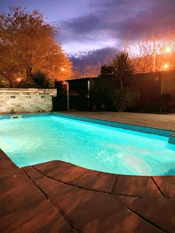 a large blue swimming pool in a yard at night at Adonai, departamentos in El Bolsón