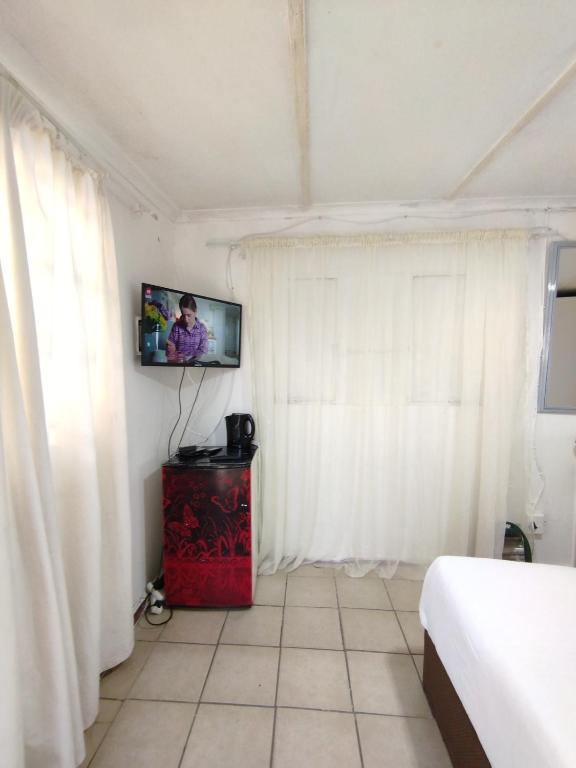 a room with a bed and a tv on the wall at affordable room rustenburg in Kroondal