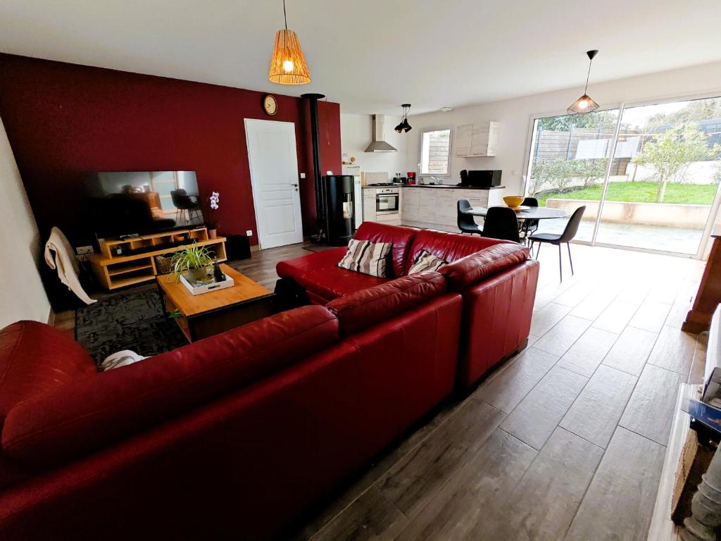 a living room with a red couch and a kitchen at Tamaris Abba in Talmont