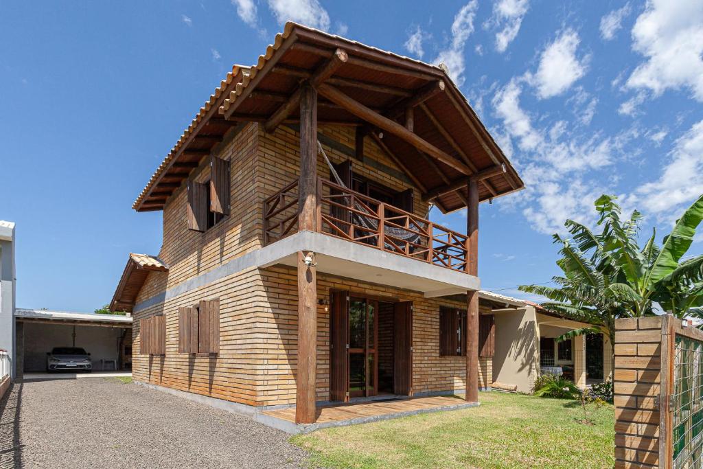 a wooden house with a balcony on top of it at Casa de veraneio na Itapeva in Torres