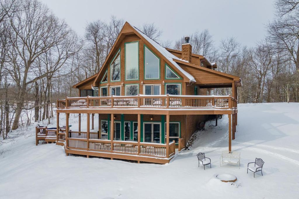 a log home with a wrap around deck in the snow at The Cozy Perch by Railey Vacations in Oakland