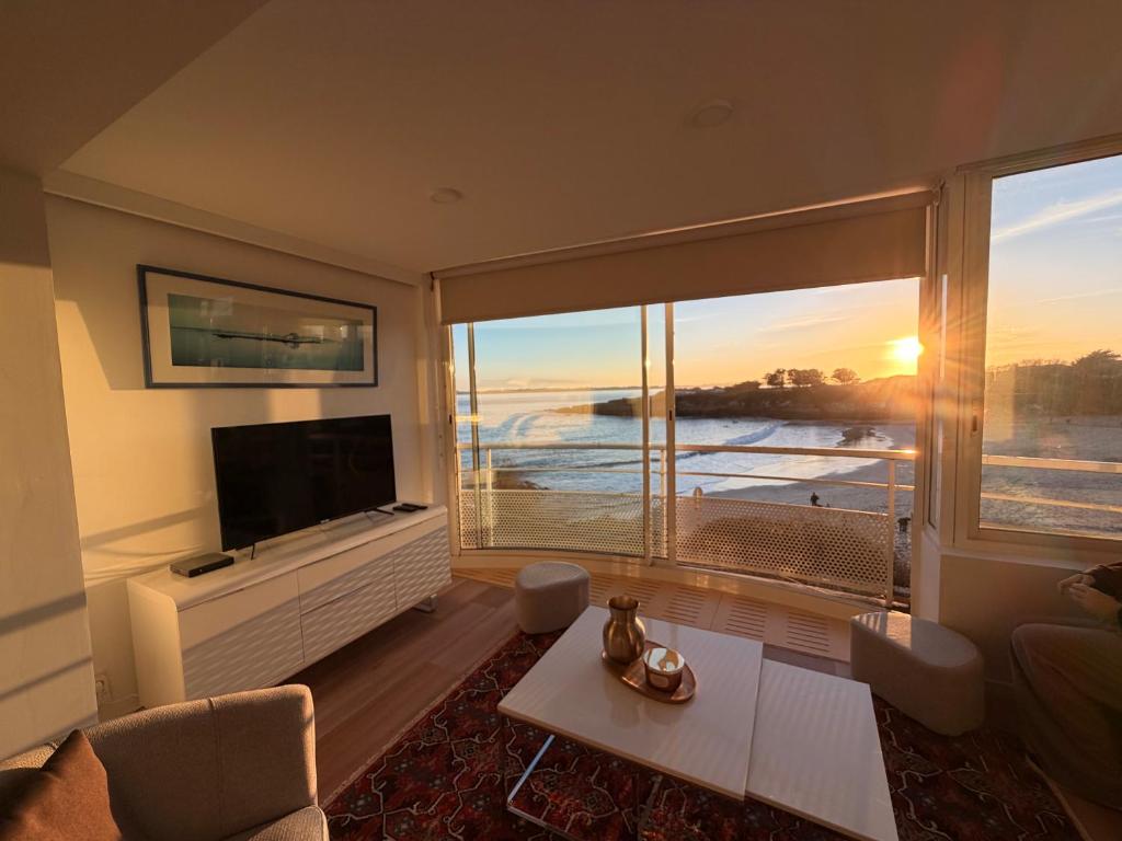a living room with a television and a large window at Le Baloo vue sur mer in Ploemeur